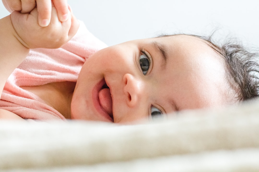 A collection of essential baby items including diapers, bottles, and toys arranged neatly on a soft blanket.