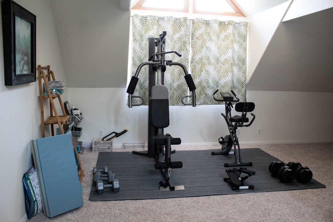 A selection of essential fitness gear for home workouts, including dumbbells, resistance bands, and a yoga mat in a cozy living room setting.