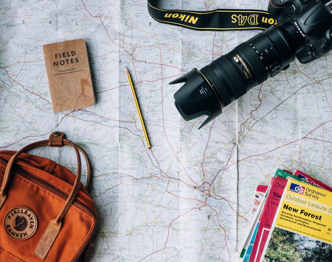 A collection of essential travel gear including a backpack, travel pillow, and packing cubes arranged on a wooden surface.