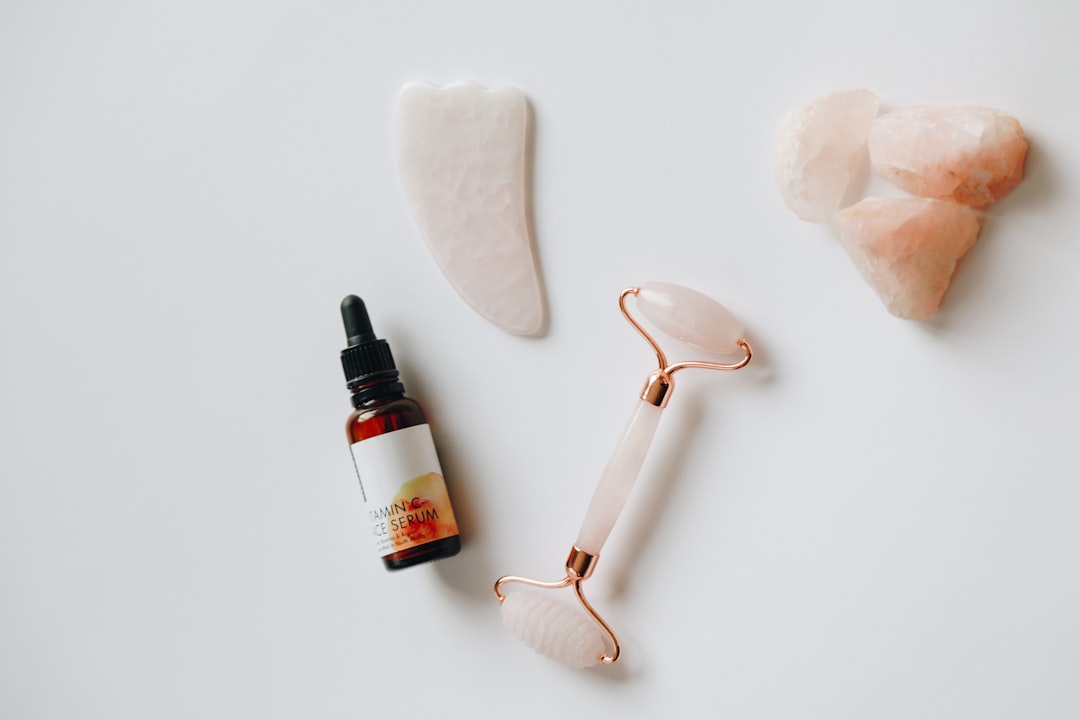 A collection of various skin care tools including facial rollers, cleansing brushes, and serums arranged aesthetically on a bathroom countertop.